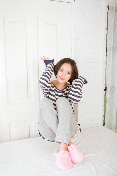 美丽的亚洲女孩坐在床上素材图片