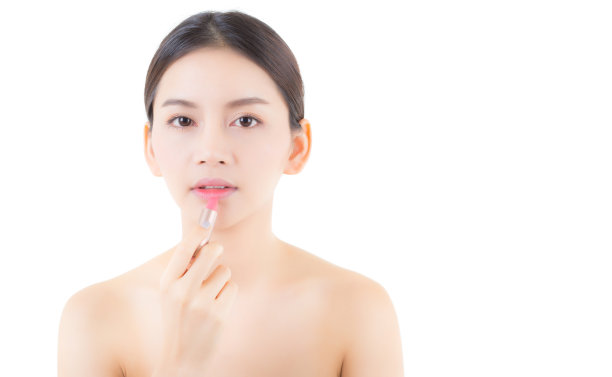 使用润唇膏的亚洲女性唇妆。快乐的亚洲女孩唇部护理，美妆化妆品概念素材图片