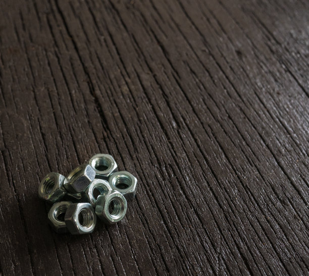 靠近螺母，紧固件在深棕色的木制背景图片下载