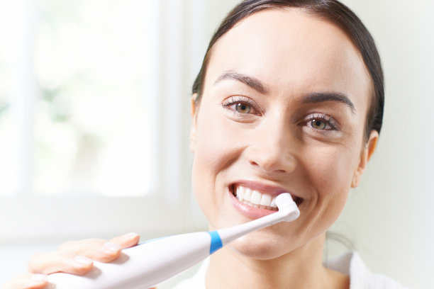 在浴室用电动牙刷刷牙的女人素材图片