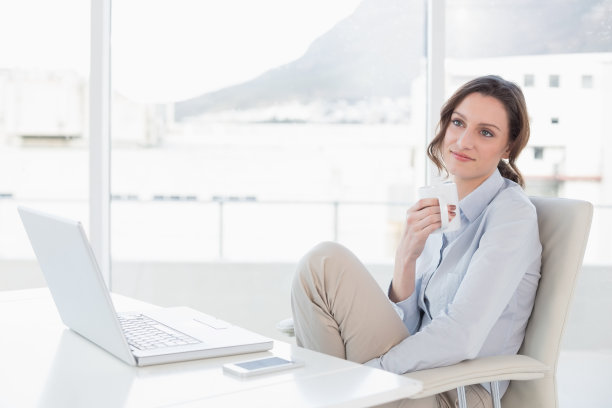 拿着笔记本电脑在办公室喝咖啡的女商人图片下载