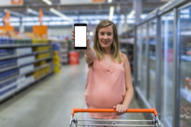 拿着手机和模糊超市的女人图片下载