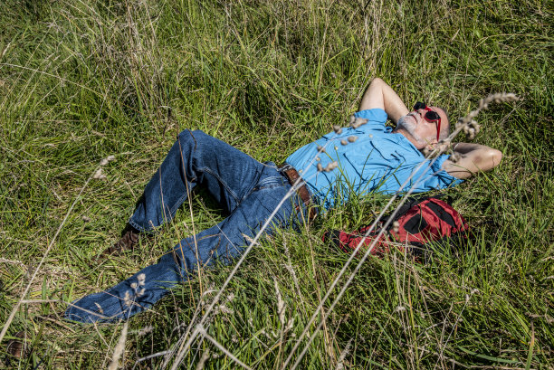 背着背包的男人躺在草地上图片下载