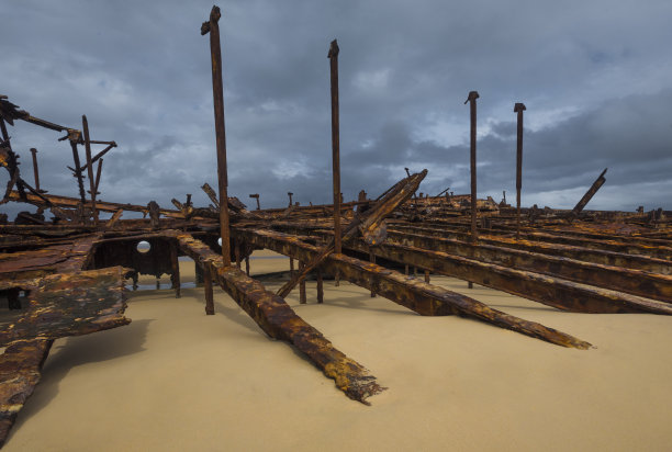 海难躺在澳大利亚弗雷泽岛的海滩上，一半被沙子覆盖。复古的金属碎片图片下载