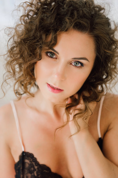 性感的女人在床上早上显示她美丽的身体。在她卧室的自然光中醒来，盖上床单。处理过的照片。图片下载