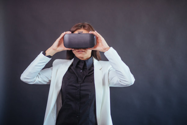 在演播室黑色背景上的快乐女人获得使用vr眼镜虚拟现实耳机的体验。图片下载