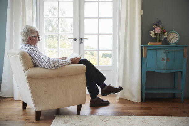老人坐在家里的扶手椅上看书图片下载