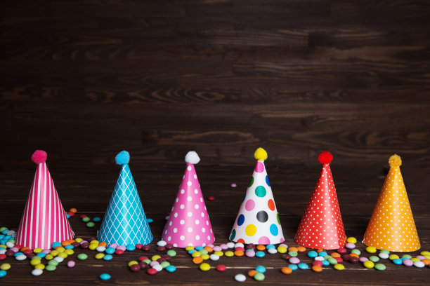 孩子们聚会的背景。生日的背景。色彩缤纷的派对帽子派对上的木制背景图片下载