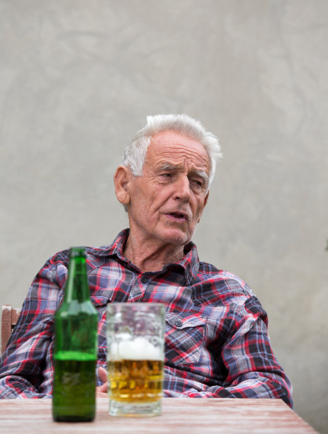 老男人拿着啤酒瓶和马克杯图片下载