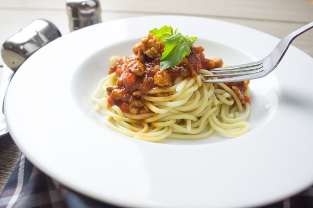 带番茄酱的意大利肉酱面，木制背景自制的健康意大利面，用叉子夹着意大利面图片下载