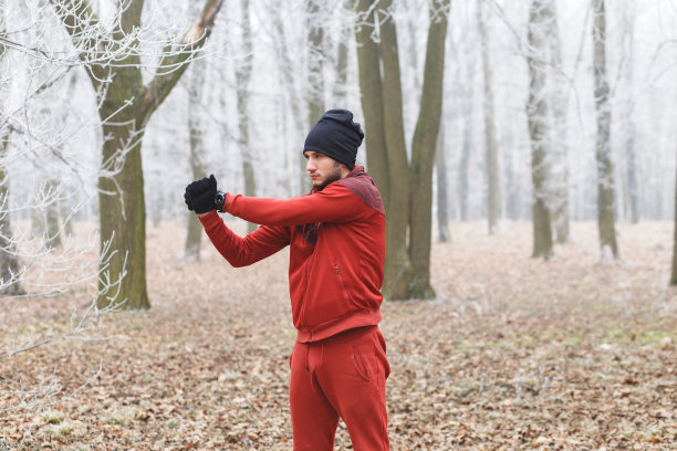 这个年轻人在寒冷的冬日里伸展肌肉，然后去森林里跑步。图片下载
