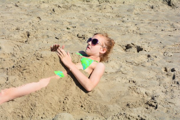 一个白人女孩在沙子里挖图片下载