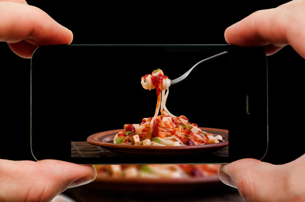 用智能手机拍意大利面。过程的特写视图。文件包含智能手机和手的剪切路径和图片上。图片下载