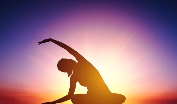 在日落背景下做瑜伽的剪影女人图片下载
