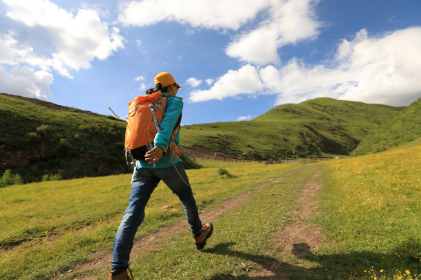 在大草原山区徒步旅行的背包女图片下载