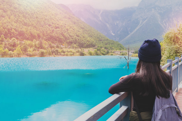 以玉龙雪山为背景的女游客在湖边旅游。中国云南。图片下载