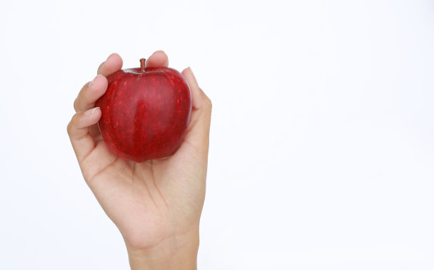 一位女士手牵着手，在白色的背景上展示一个红苹果。图片下载