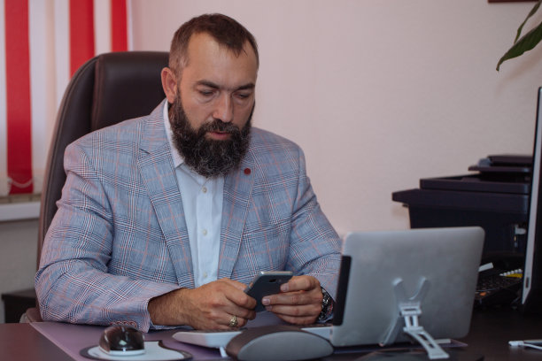 在办公室使用移动电话的商人。图片下载