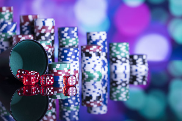赌场的主题。高对比度图像赌场轮盘赌，扑克游戏，骰子游戏，扑克筹码在赌桌上，所有在彩色的散景背景。图片下载