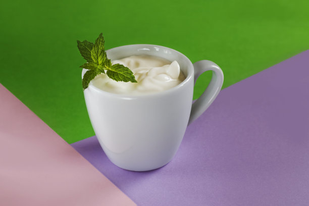 最小的创意概念。牛奶甜点在一个白色的杯子，装饰薄荷在绿色图片下载