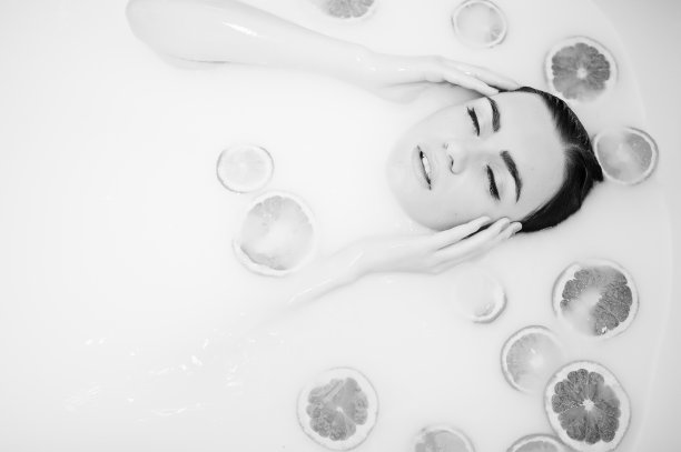 性感的黑发女孩在浴室喝着牛奶和水果。青春沐浴身体。图片下载