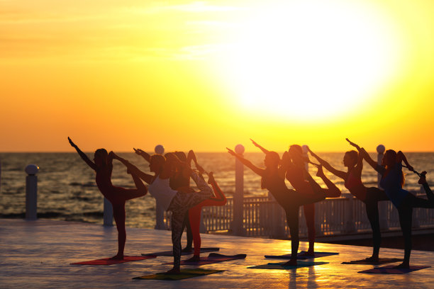 日出时，一群妇女在海边做瑜伽图片下载