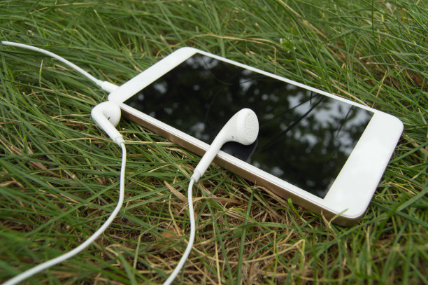 把智能手机和耳机放在绿草地上，休息一下图片下载