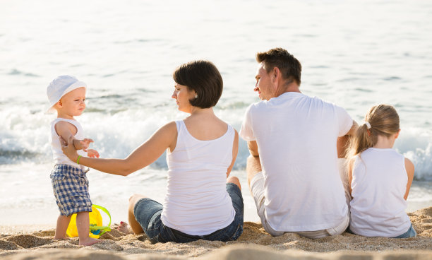 快乐的父母和孩子坐在后面向前图片下载