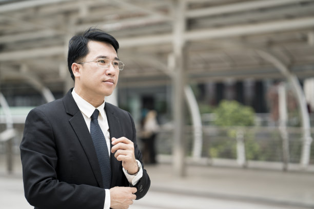 年轻自信的亚洲商人穿着西装站在城市户外。图片下载