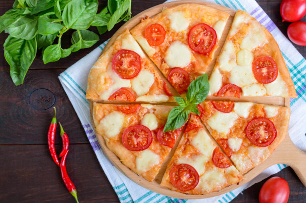 经典的意大利玛格丽塔披萨，以马苏里拉奶酪、西红柿和罗勒为背景，以深色的木头为背景。图片下载