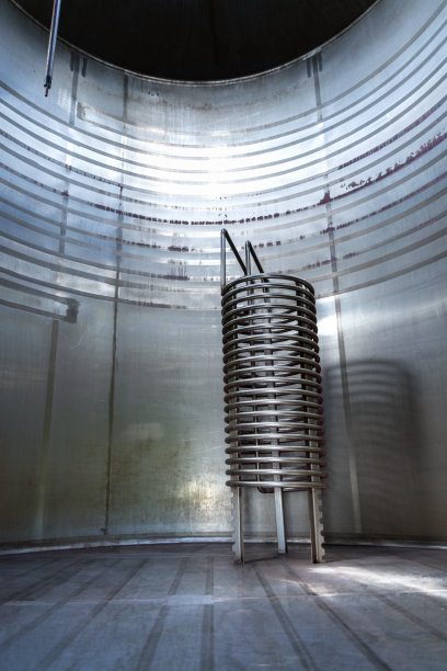 酒窖内的金属酒桶，装在装有加热系统的大空酒桶内图片下载