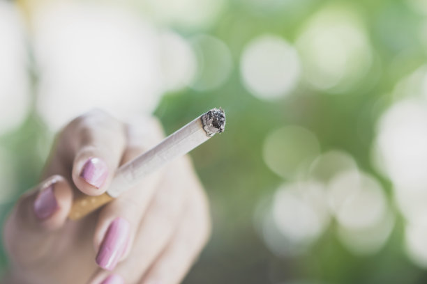 女人在户外手握香烟吸烟，不健康的观念图片下载