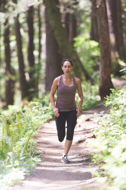 坚定的年轻女子在林中小径上奔跑图片下载