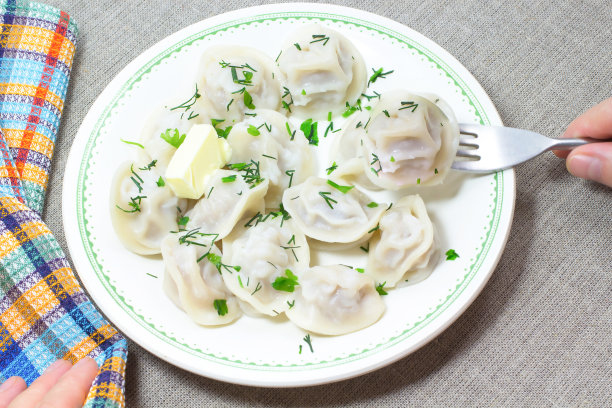在碗里撒上莳萝和黄油的煮饺子。彩色餐巾纸图片下载