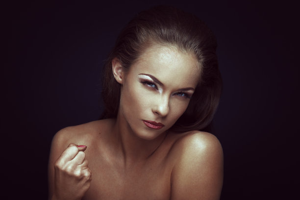 在黑暗的背景下，一个愤怒的女人握紧了拳头图片下载