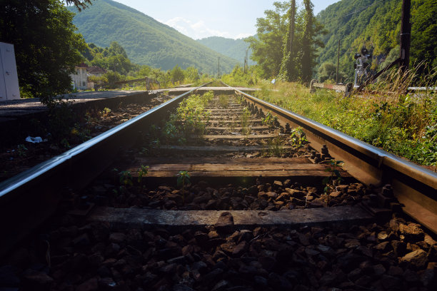 低角度的铁路轨道与减少的视角导致郁郁葱葱的绿色山脉图片下载
