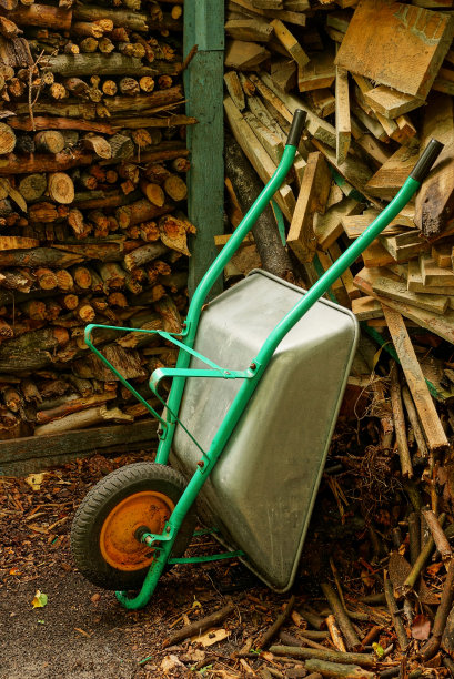 一辆装着干柴火的铁手推车靠墙站着图片下载
