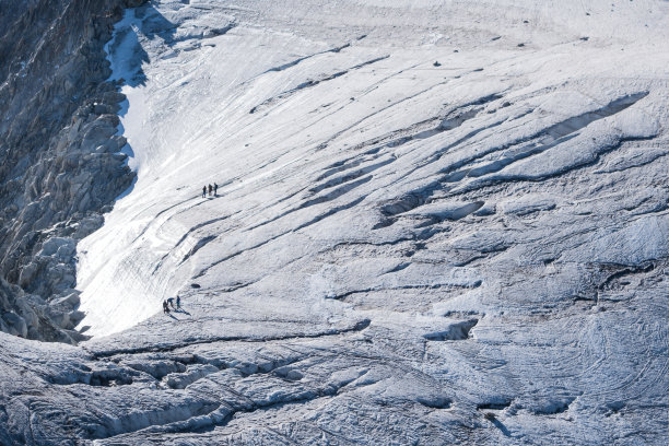 在夏季，用绳索固定的步行者穿越高山冰川图片下载
