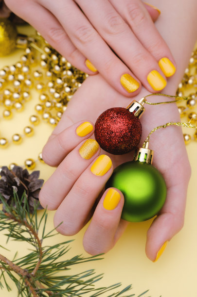 漂亮的女性手与黄色指甲设计。圣诞修指甲。图片下载