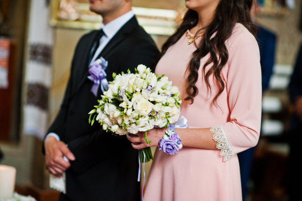 近距离的照片，一个伴娘拿着一束花在教堂在婚礼上。图片下载