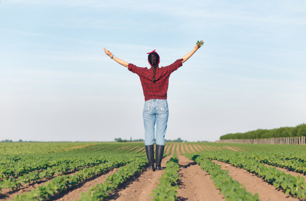 一位女农民伸开双臂站在麦田里。图片下载