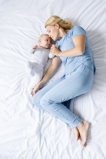 妈妈挨着婴儿睡在床上素材图片