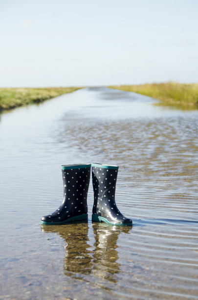 蓝色的孩子们的胶靴上有白点被单独留在了一条流出海洋的水道里这是斯堪的纳维亚自然的水道图片下载