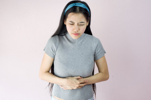 亚洲或泰国美丽的女人的手触摸她的胃，生病的胃痛感觉压力在粉红色的背景图片下载