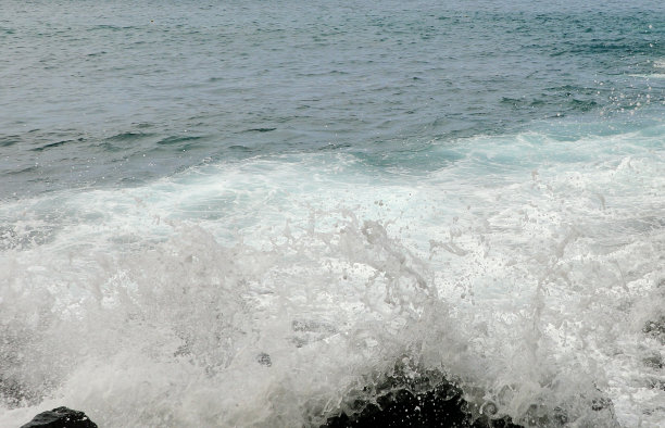惊涛骇浪拍打着石滩。水蓝色背景。图片下载