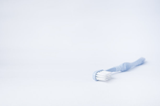 蓝色的牙刷放在白色的背景上，侧面的灯光从外面和复制空间在图像图片下载