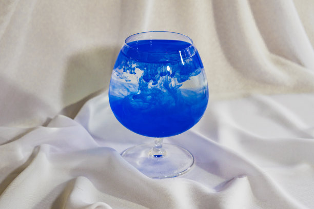 玻璃杯里的蓝色水彩画。颜色在玻璃中混合。油彩在水中。图片下载