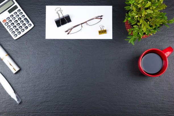 黑色的办公桌桌上有电脑，钢笔和一杯咖啡，很多东西。顶部视图与复制空间图片下载