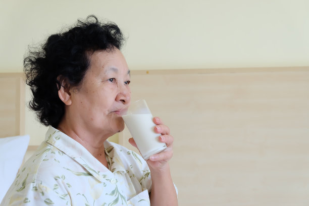 亚洲资深妇女在床上喝牛奶图片下载