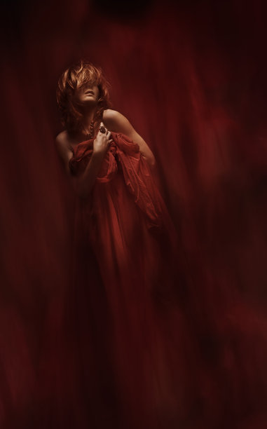 时装模特艺术肖像，女人在红色裙子摆姿势在黑暗的背景图片下载